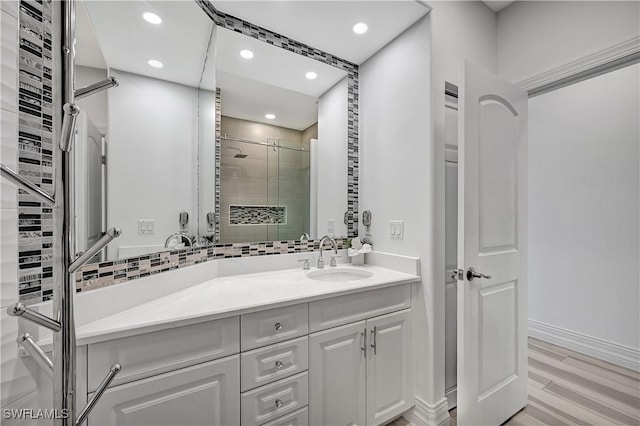 bathroom with recessed lighting, wood finished floors, vanity, decorative backsplash, and a stall shower