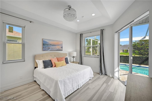 bedroom with baseboards, a raised ceiling, access to exterior, light wood-style floors, and recessed lighting