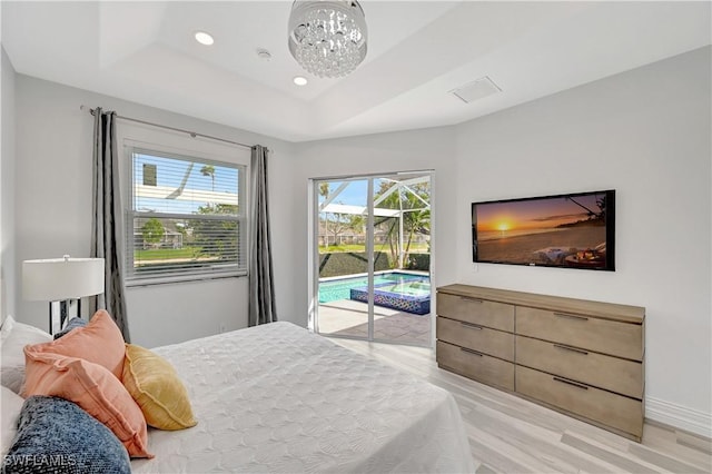 bedroom featuring baseboards, access to exterior, a tray ceiling, a notable chandelier, and recessed lighting