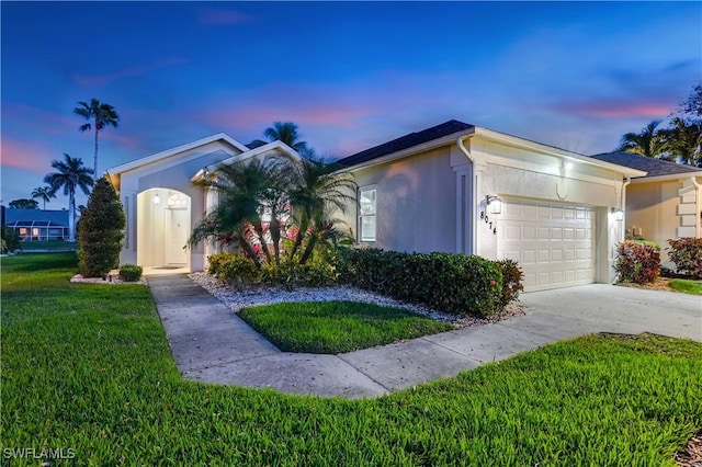 single story home featuring a garage, a front yard, driveway, and stucco siding