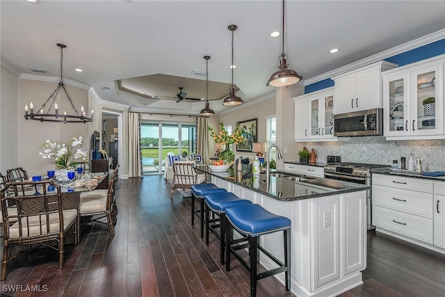 kitchen with white cabinets, glass insert cabinets, stainless steel microwave, pendant lighting, and a sink