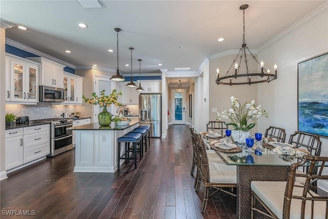 dining space featuring ornamental molding, visible vents, dark wood finished floors, and a notable chandelier