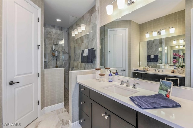 bathroom featuring marble finish floor, tile walls, vanity, and a walk in shower