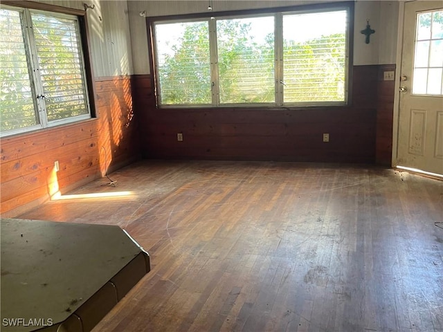 empty room with hardwood / wood-style floors and wooden walls