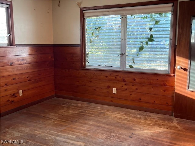 unfurnished room featuring a wainscoted wall, wooden walls, and wood finished floors