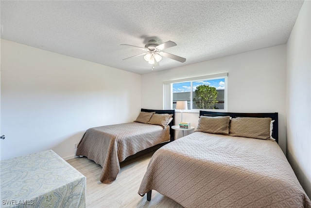 bedroom with light wood-type flooring, a textured ceiling, and a ceiling fan