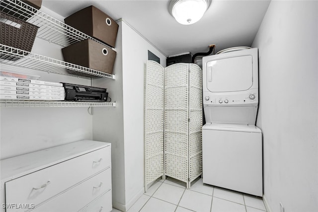 laundry area featuring laundry area, light tile patterned floors, baseboards, and stacked washer / dryer