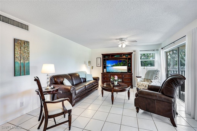 living area featuring visible vents, ceiling fan, a textured ceiling, and light tile patterned floors