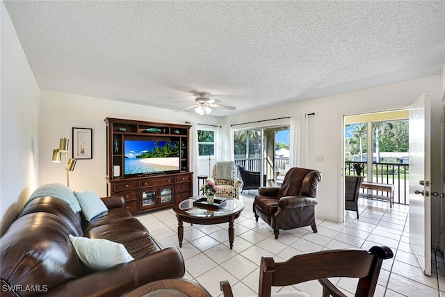 living room featuring light tile patterned floors, ceiling fan, and a textured ceiling