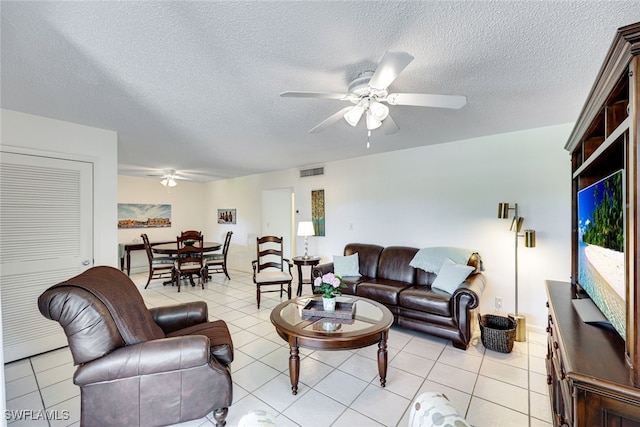 living room featuring visible vents, ceiling fan, a textured ceiling, and light tile patterned floors