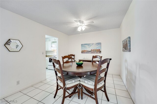 dining room featuring a textured ceiling, light tile patterned floors, a ceiling fan, and baseboards