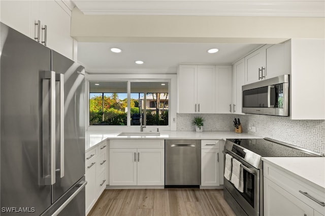 kitchen featuring a sink, backsplash, appliances with stainless steel finishes, light wood finished floors, and light countertops