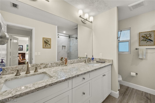 ensuite bathroom with a sink, a marble finish shower, toilet, and visible vents