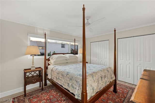 bedroom with ornamental molding, baseboards, multiple closets, and wood finished floors