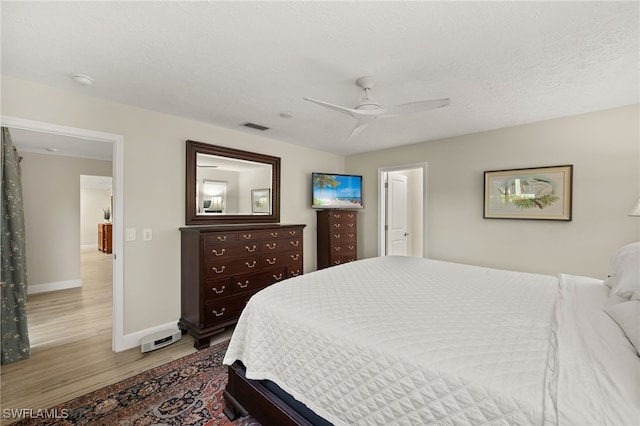 bedroom with visible vents, ceiling fan, baseboards, light wood-style floors, and a textured ceiling