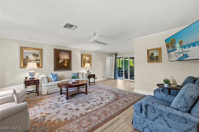 living area with light wood finished floors, visible vents, ceiling fan, baseboards, and ornamental molding