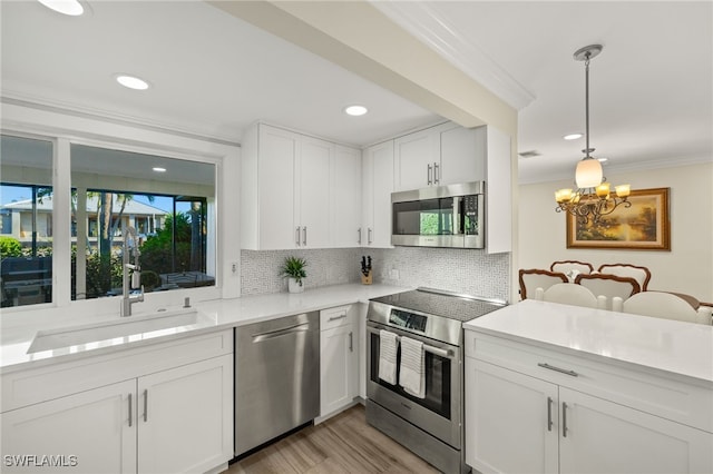 kitchen with ornamental molding, a sink, light countertops, appliances with stainless steel finishes, and backsplash