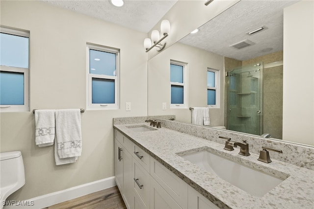 full bathroom with a sink, toilet, a stall shower, and a textured ceiling