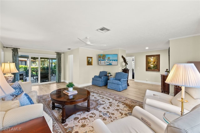 living area with crown molding, wood finished floors, visible vents, and baseboards