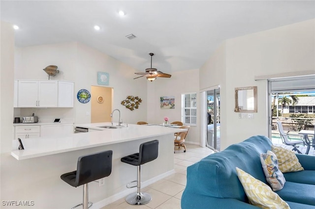 kitchen with visible vents, white cabinets, a kitchen bar, a sink, and light tile patterned flooring