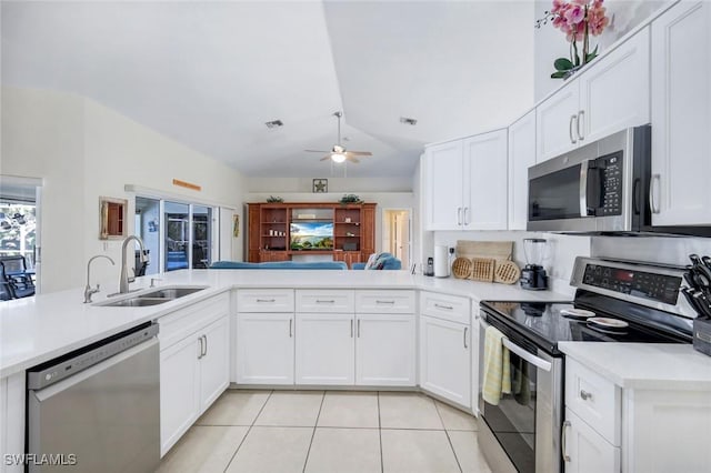 kitchen featuring light tile patterned floors, stainless steel appliances, a sink, vaulted ceiling, and light countertops