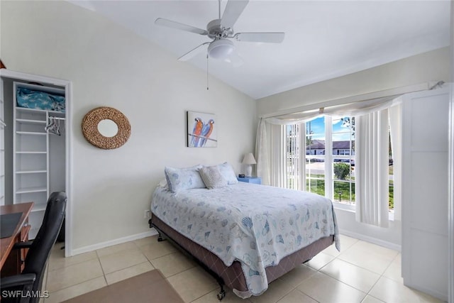 bedroom featuring a walk in closet, light tile patterned flooring, vaulted ceiling, and baseboards