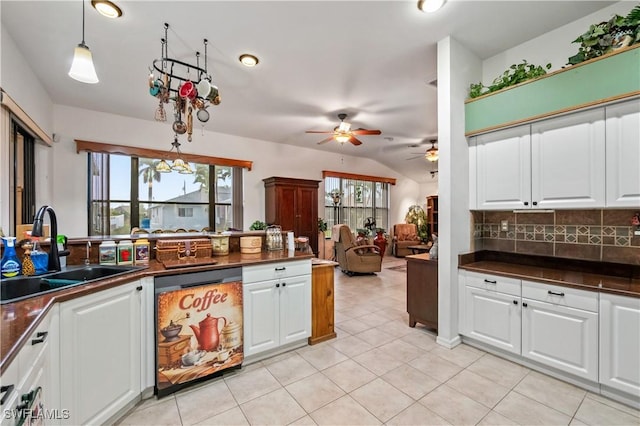 kitchen featuring dark countertops, dishwashing machine, a ceiling fan, and a sink