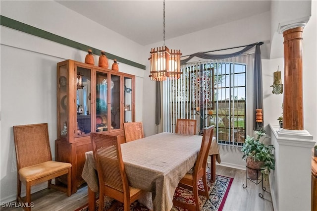 dining room with an inviting chandelier, decorative columns, wood finished floors, and baseboards