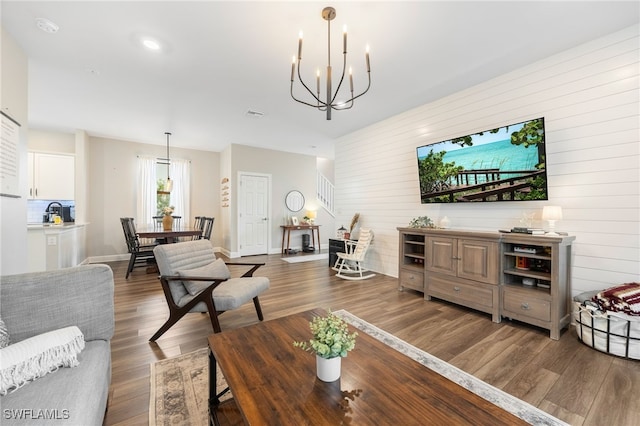 living room featuring visible vents, dark wood-type flooring, baseboards, stairs, and a notable chandelier