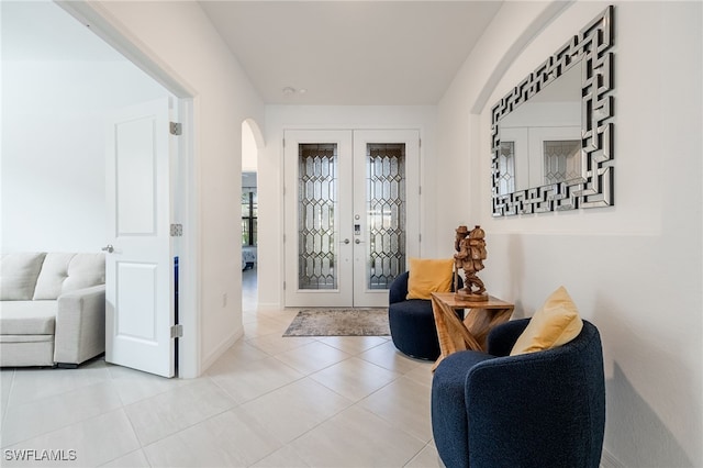 foyer entrance with tile patterned flooring, french doors, arched walkways, and baseboards