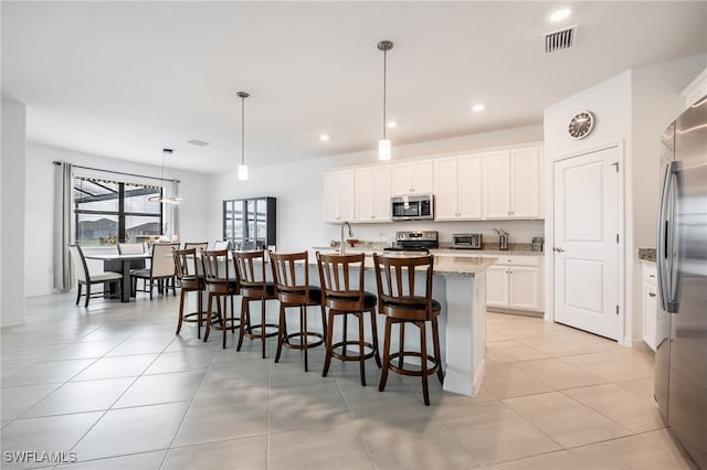 kitchen featuring a center island with sink, light tile patterned flooring, visible vents, and appliances with stainless steel finishes