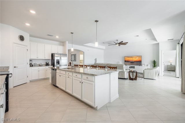 kitchen with a sink, white cabinetry, stainless steel appliances, arched walkways, and ceiling fan