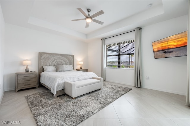 bedroom with light tile patterned floors, baseboards, and a raised ceiling