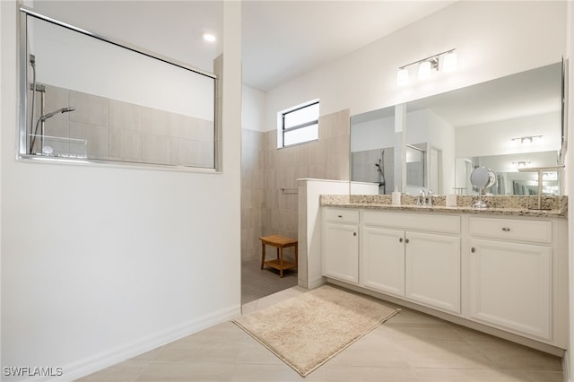 full bath featuring vanity, baseboards, tile patterned flooring, and walk in shower