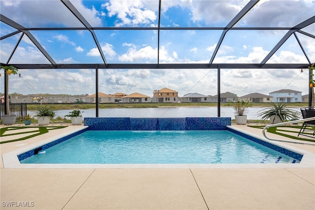 outdoor pool featuring glass enclosure, a residential view, a patio, and a water view