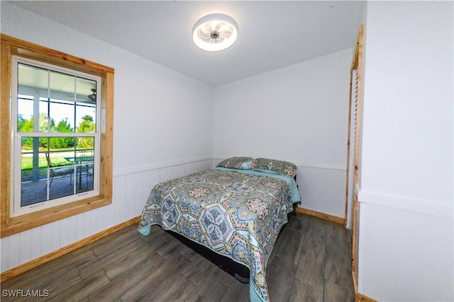 bedroom featuring wainscoting and dark wood finished floors