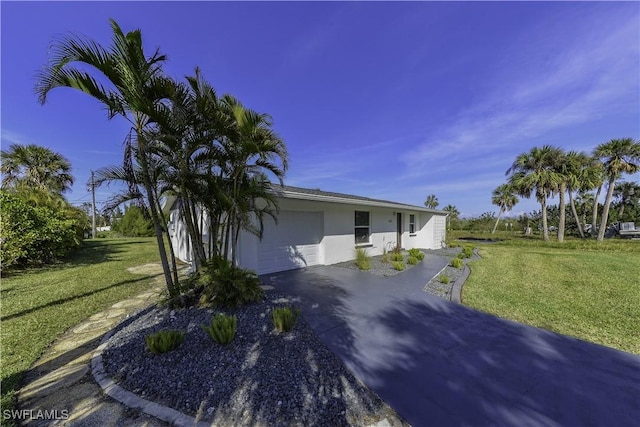 view of property exterior with a garage, aphalt driveway, a lawn, and stucco siding