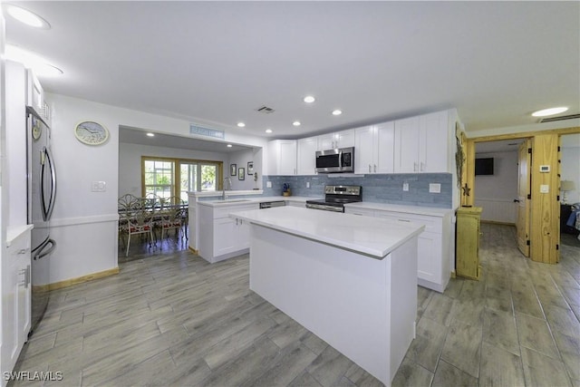 kitchen featuring a center island, light countertops, appliances with stainless steel finishes, white cabinetry, and a peninsula