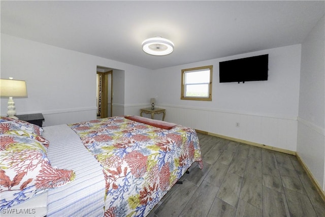 bedroom featuring wainscoting and wood finished floors