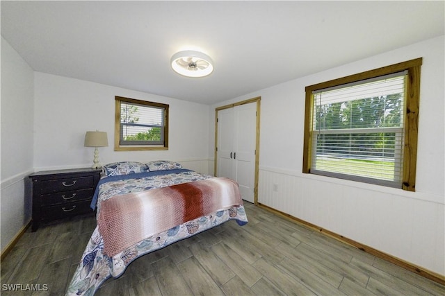 bedroom featuring a closet, a wainscoted wall, and wood finished floors