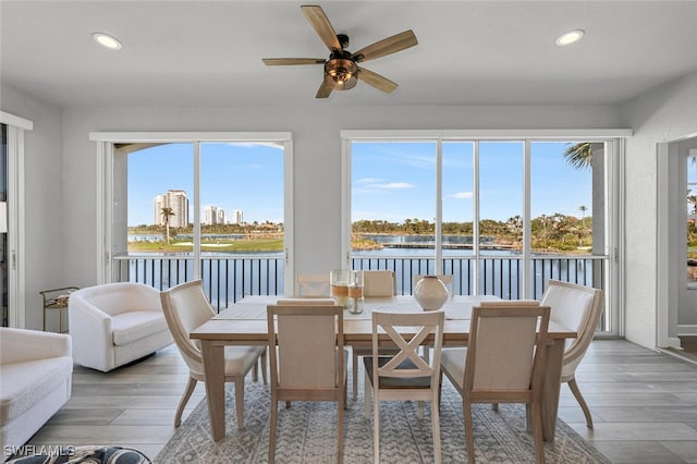 sunroom with a wealth of natural light, a water view, and a ceiling fan