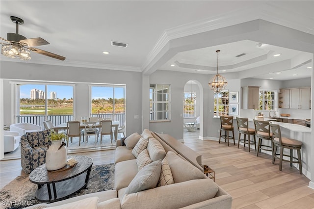 living room with light wood-style floors, a wealth of natural light, ornamental molding, and baseboards