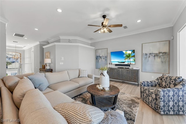 living area with ceiling fan with notable chandelier, wood finished floors, visible vents, and ornamental molding