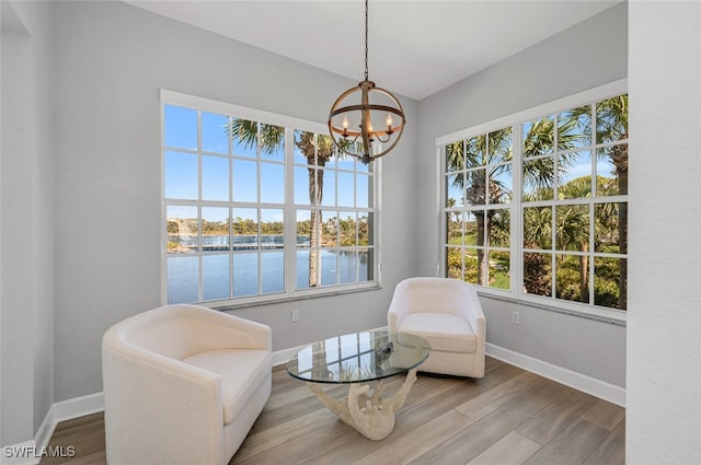 sitting room with a water view, baseboards, and wood finished floors