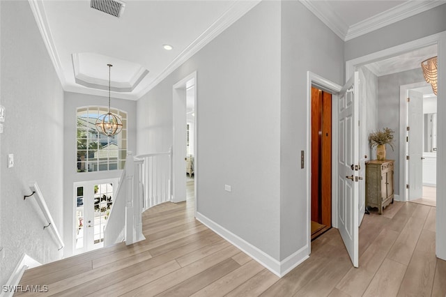 hallway with visible vents, an upstairs landing, ornamental molding, light wood-type flooring, and an inviting chandelier