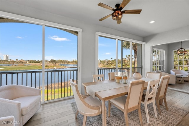 sunroom with a ceiling fan and a water view