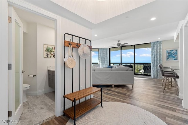 interior space featuring toilet, baseboards, a wall of windows, and wood finished floors