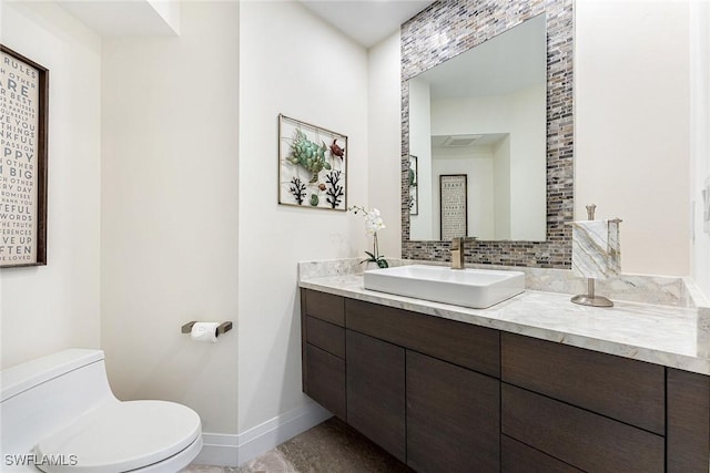 bathroom featuring visible vents, decorative backsplash, toilet, vanity, and baseboards