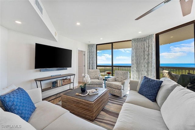 living area with a wall of windows, a water view, visible vents, and recessed lighting