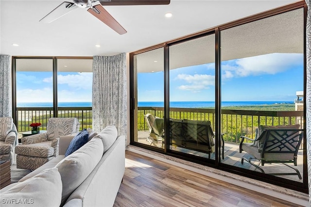 living area with recessed lighting, a water view, wood finished floors, a ceiling fan, and expansive windows